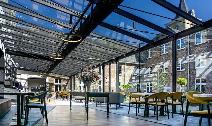 Een grote ruimte met glazen wanden en plafonds met tafels en stoelen en een bar